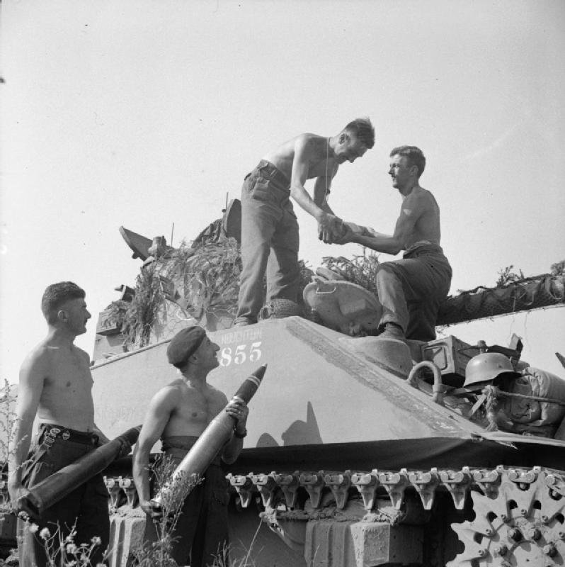 Crew of a Sherman Firefly, 1st Northamptonshire Yeomanry, loading 17-pounder ammunition before Operation Totalise, 7 August 1944.