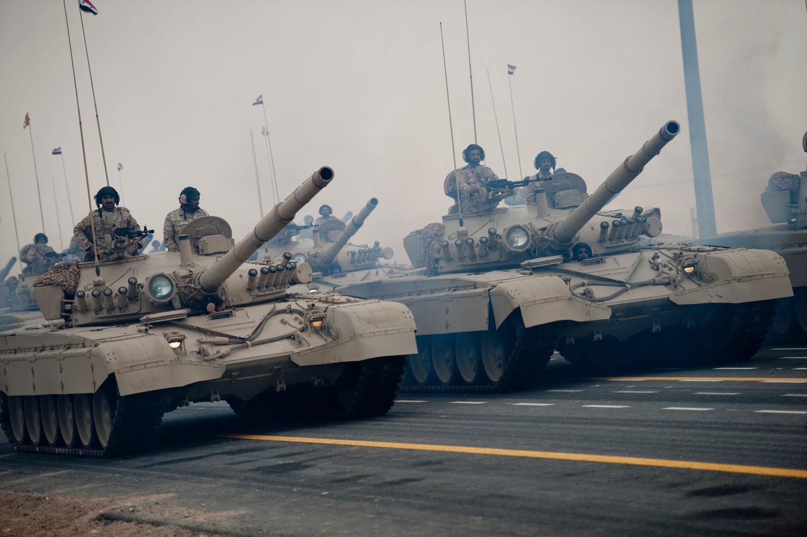 Kuwaiti M-84 tanks parading during Kuwait National and Liberation Day celebrations, 26 February 2011, Kuwait City. Vehicle/variant identification: file title identifies M-84AB-family tanks in Kuwaiti service. captions on the file page mention Syrian flags during the parade. [S15].