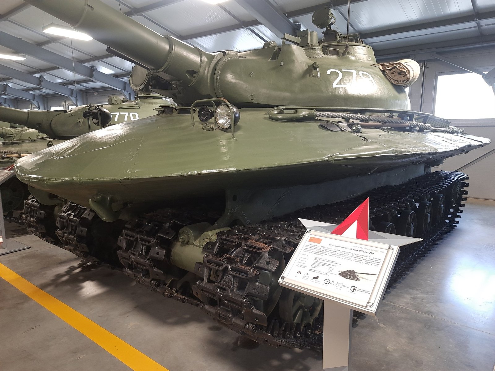 Recent museum display view of Object 279 with exhibit placard and turret number visible. Object 279 prototype. 11 October 2024. Kubinka Tank Museum / Patriot Park display area, Russia; camera location listed on file page as 55.565000, 36.716000. Shows current museum status; neighboring Object 770 is visible in background. [S5].