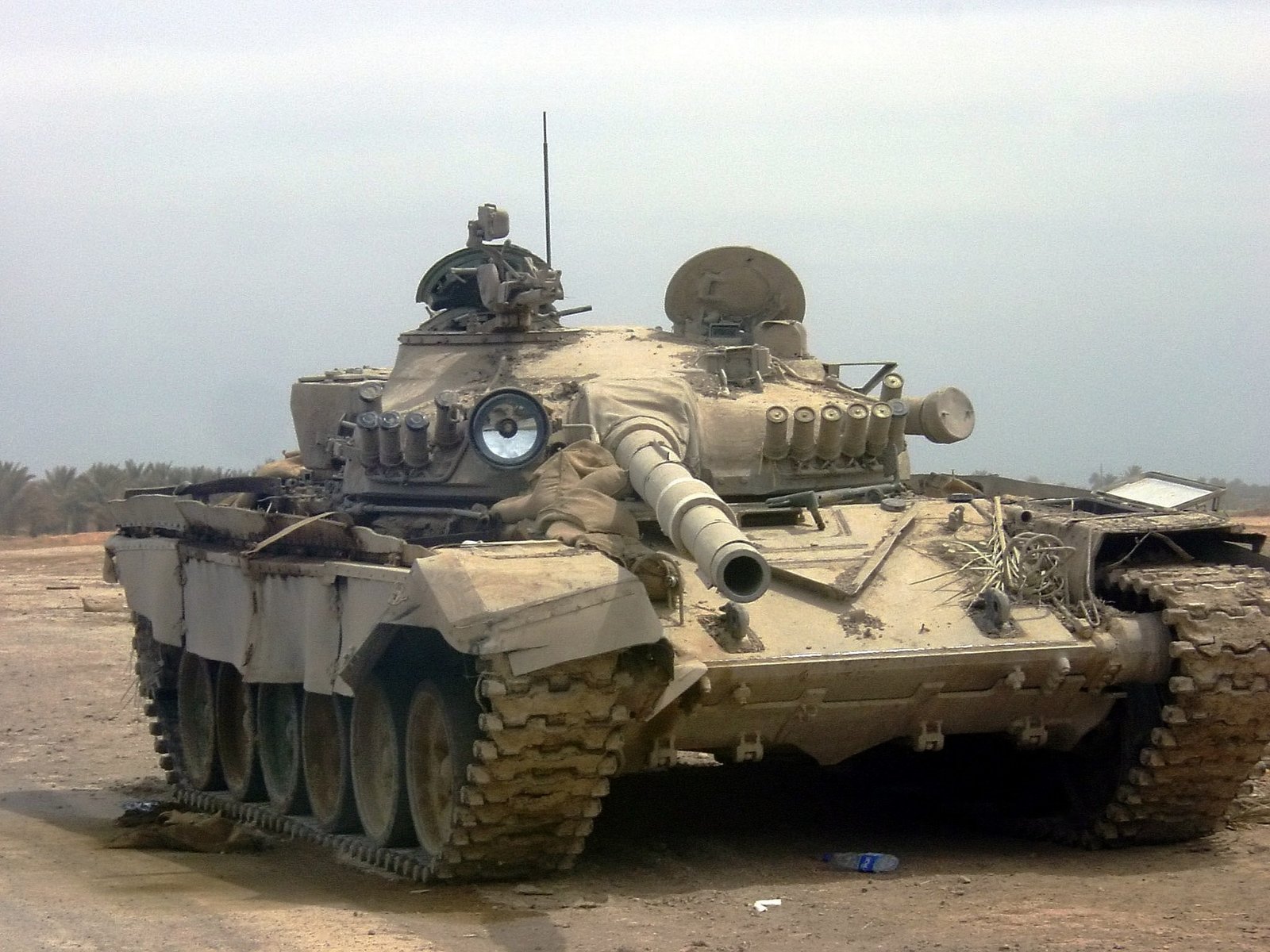 Derelict Asad Babil / Iraqi T-72 abandoned on a U.S. main supply route in Iraq, 27 May 2003. Vehicle/variant identification: Commons describes reinforced glacis and bracket for electro-optical countermeasures pod as visible. strong visual evidence of late-service condition and pod bracket; exact build origin remains unproven.