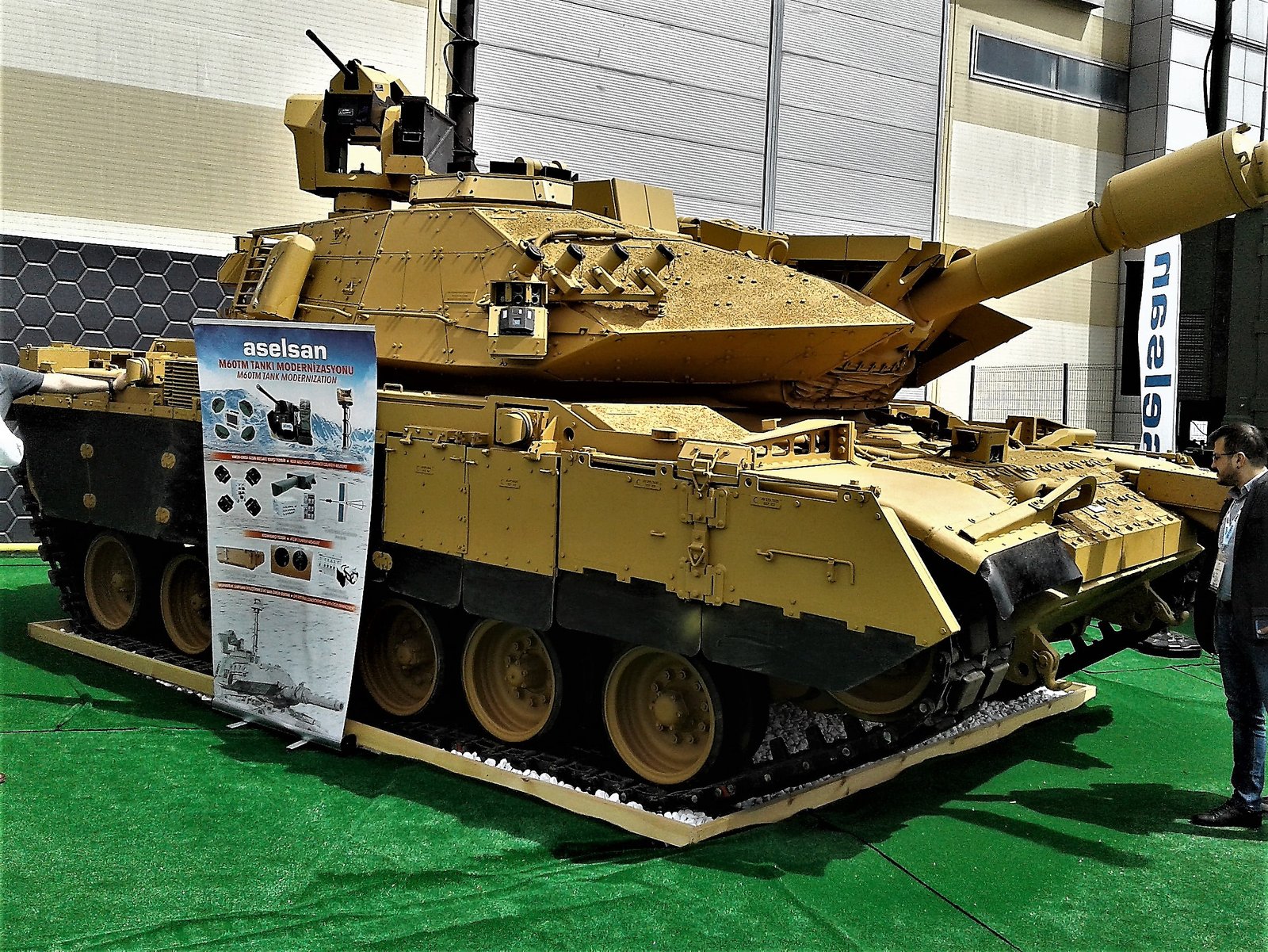 M60TM displayed by ASELSAN at IDEF 2019 in Istanbul, 2 May 2019. The image shows the Turkish post-Fırat modernization style with extensive add-on armor, sensors, and remote/topside equipment. Exhibition display; not a combat photograph.