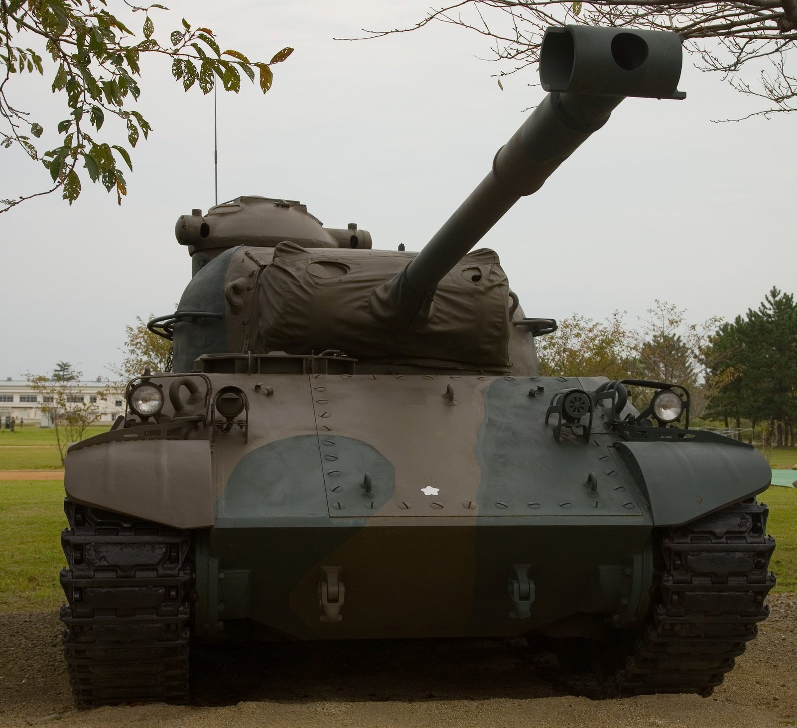 Front view of a Type 61 at the JGSDF Ordnance School, showing the 90 mm muzzle brake, glacis, driver area, and turret front.